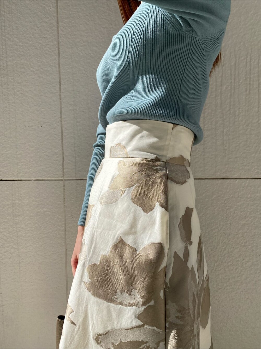 ブルー系のニット/セーター、ベージュ系のスカート、ベージュ系のハンドバッグを着用したレディースの冬コーディネートの5枚目の写真