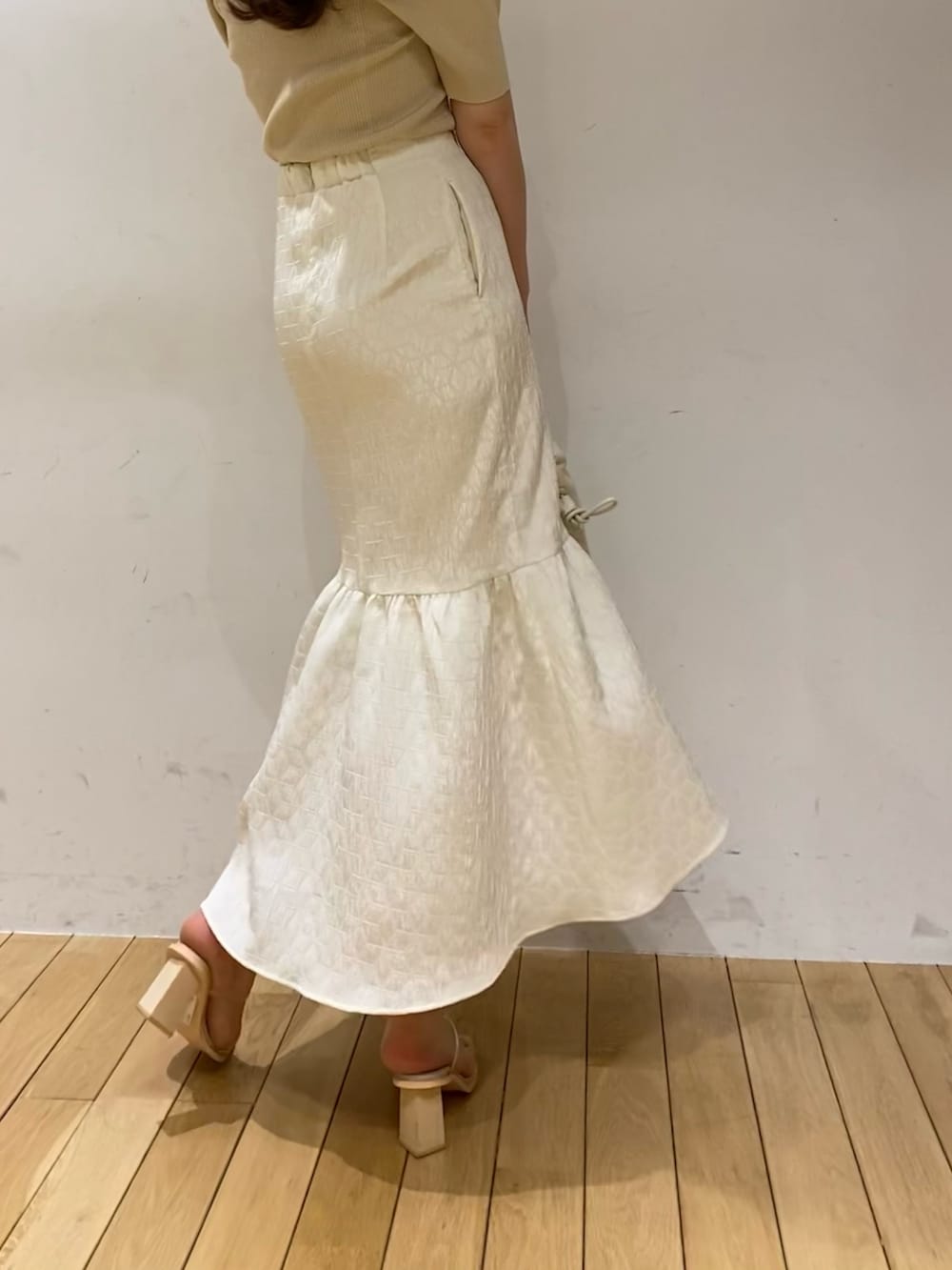 ホワイト系のスカート、ベージュ系のニット/セーター、その他のサンダルを着用したレディースの春コーディネートの2枚目の写真