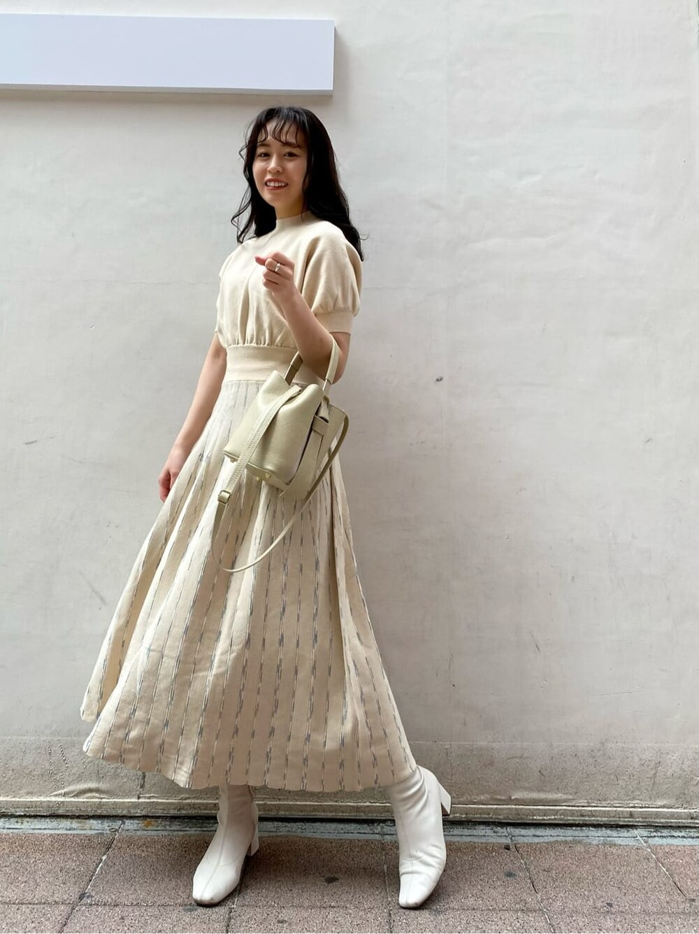 ベージュ系のトレンチコート、ホワイト系のワンピース、ホワイト系のハンドバッグを着用したレディースの春コーディネートの2枚目の写真