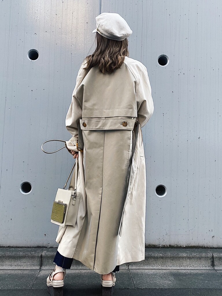 ホワイト系のトレンチコート、ホワイト系のサンダル、ホワイト系のキャップを着用したレディースの春コーディネートの3枚目の写真