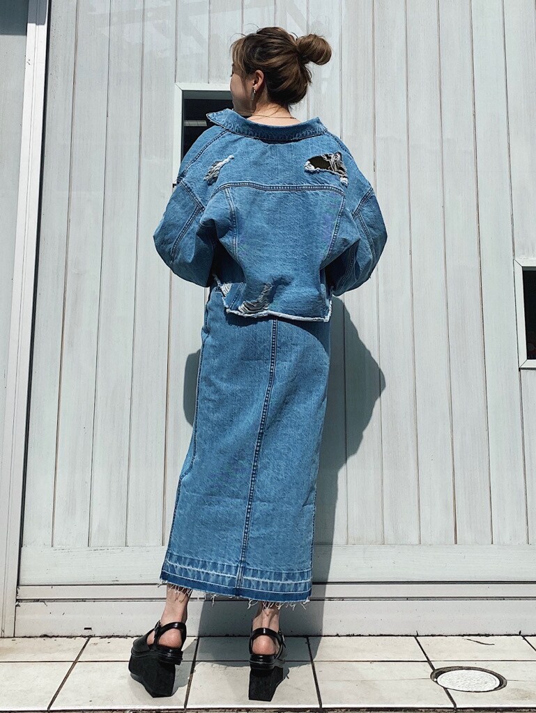 ブルー系のデニムスカート、グリーン系のニット/セーター、ブラック系のサンダルを着用したレディースの春コーディネートの3枚目の写真