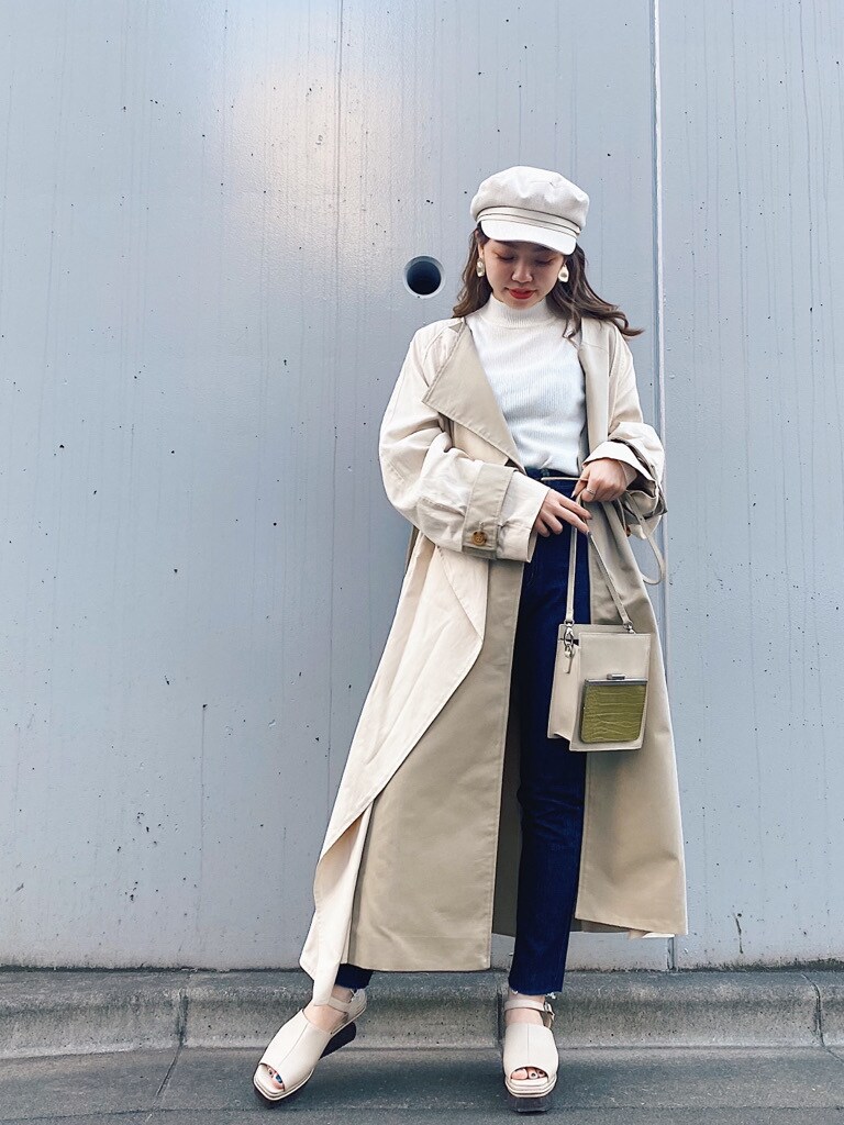ホワイト系のトレンチコート、ホワイト系のサンダル、ホワイト系のキャップを着用したレディースの春コーディネートの2枚目の写真