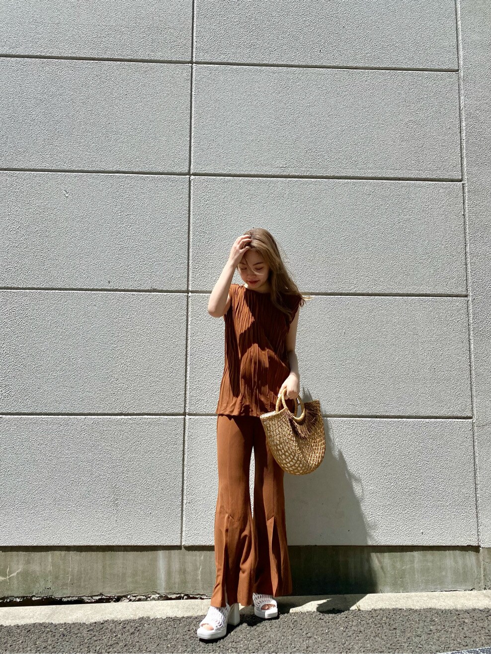 ベージュ系のかごバッグ、ブラウン系のシャツ/ブラウス、ブラウン系のスラックスを着用したレディースの夏コーディネートの2枚目の写真