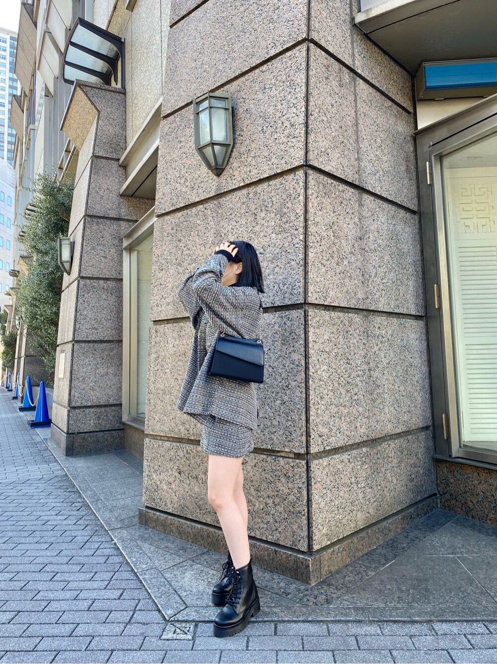 ブラック系のブーツ、ブラック系のスカート、ブラック系のハンドバッグを着用したレディースの冬コーディネートの2枚目の写真