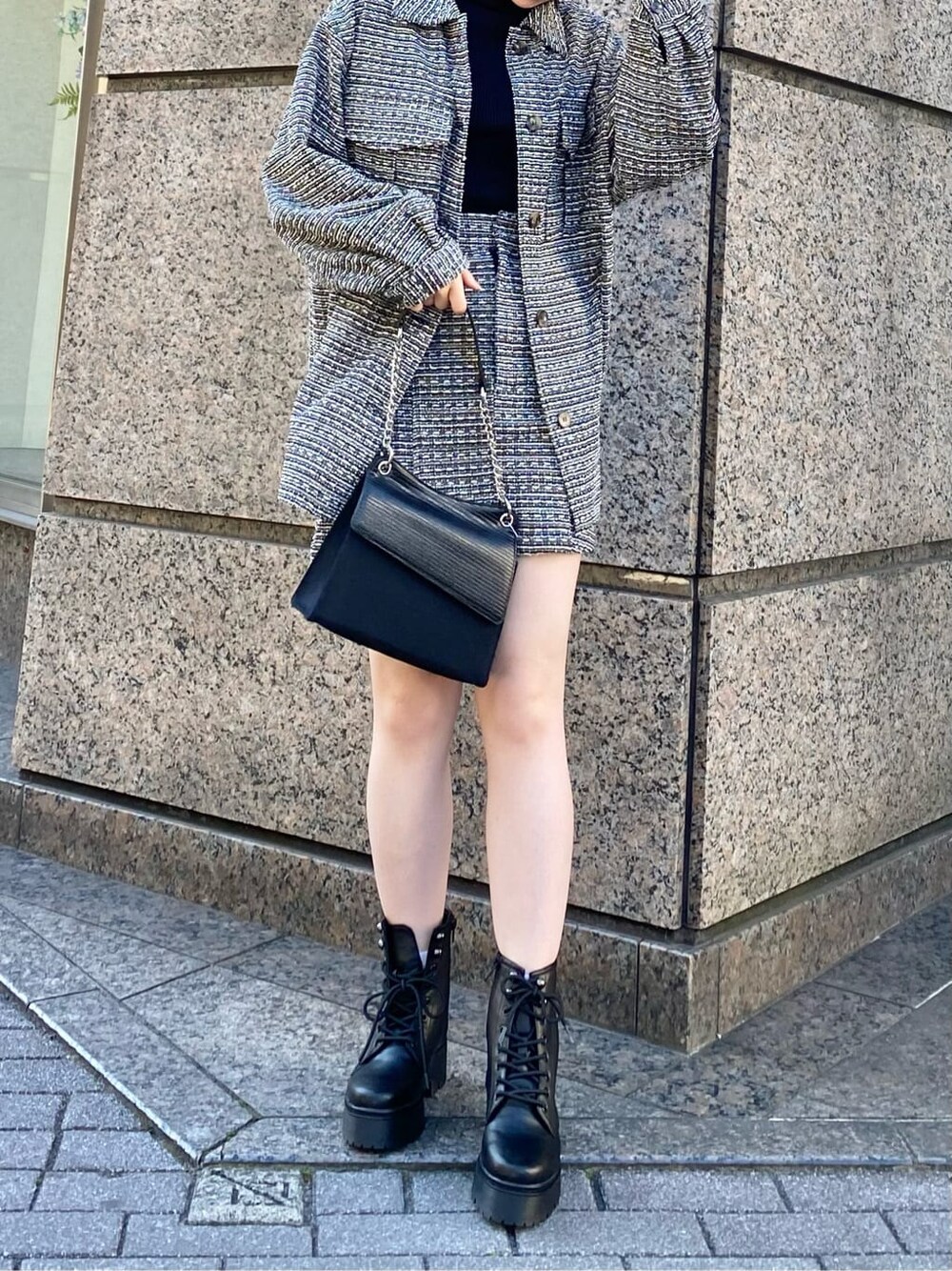 ブラック系のブーツ、ブラック系のスカート、ブラック系のハンドバッグを着用したレディースの冬コーディネートの3枚目の写真