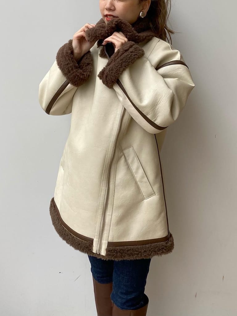 ホワイト系のブルゾン、ブラウン系のブーツを着用したレディースの秋コーディネートの2枚目の写真