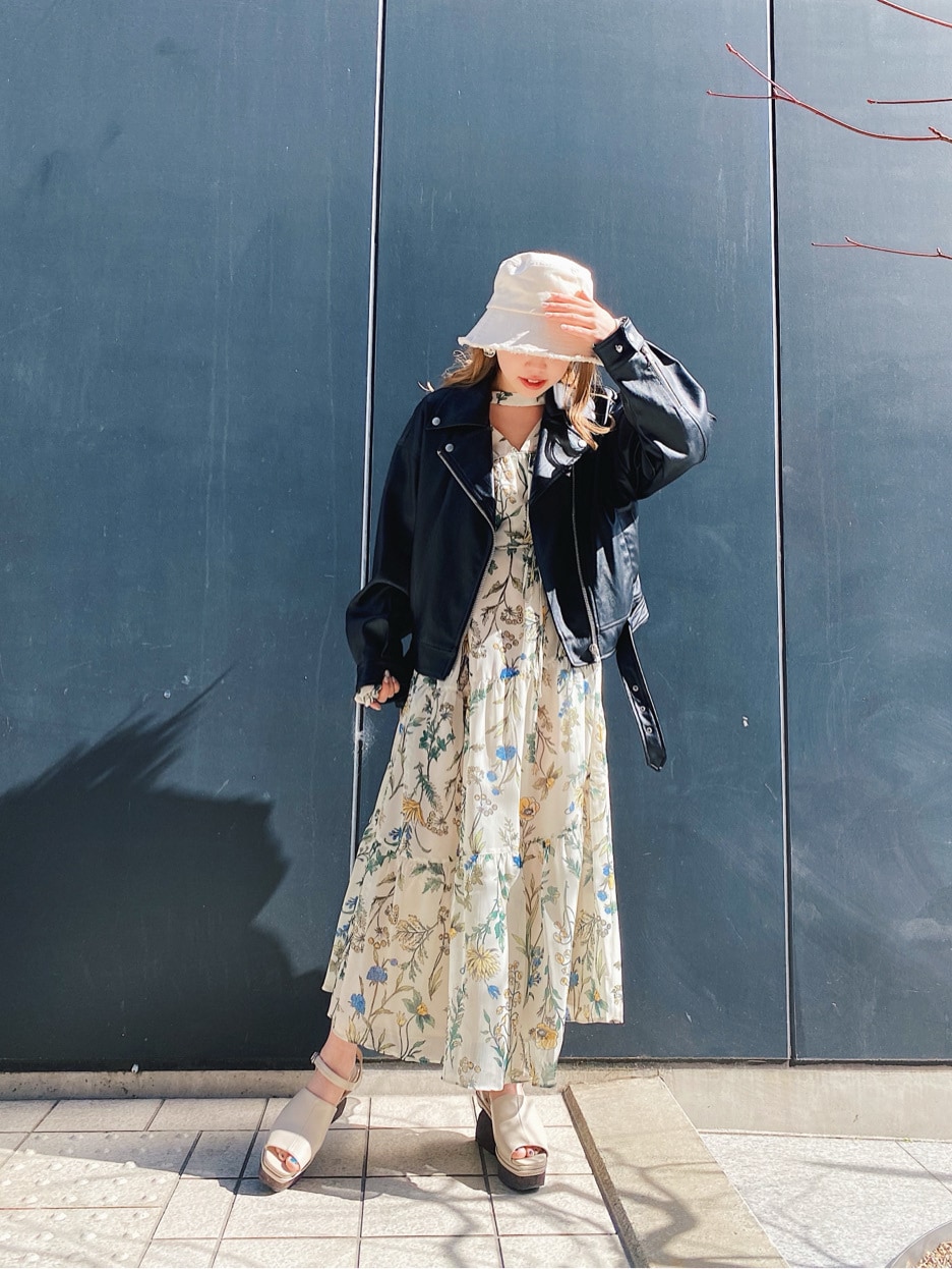 ベージュ系のワンピース、ブラック系のライダースジャケット、ホワイト系のサンダルを着用したレディースの春コーディネートの2枚目の写真