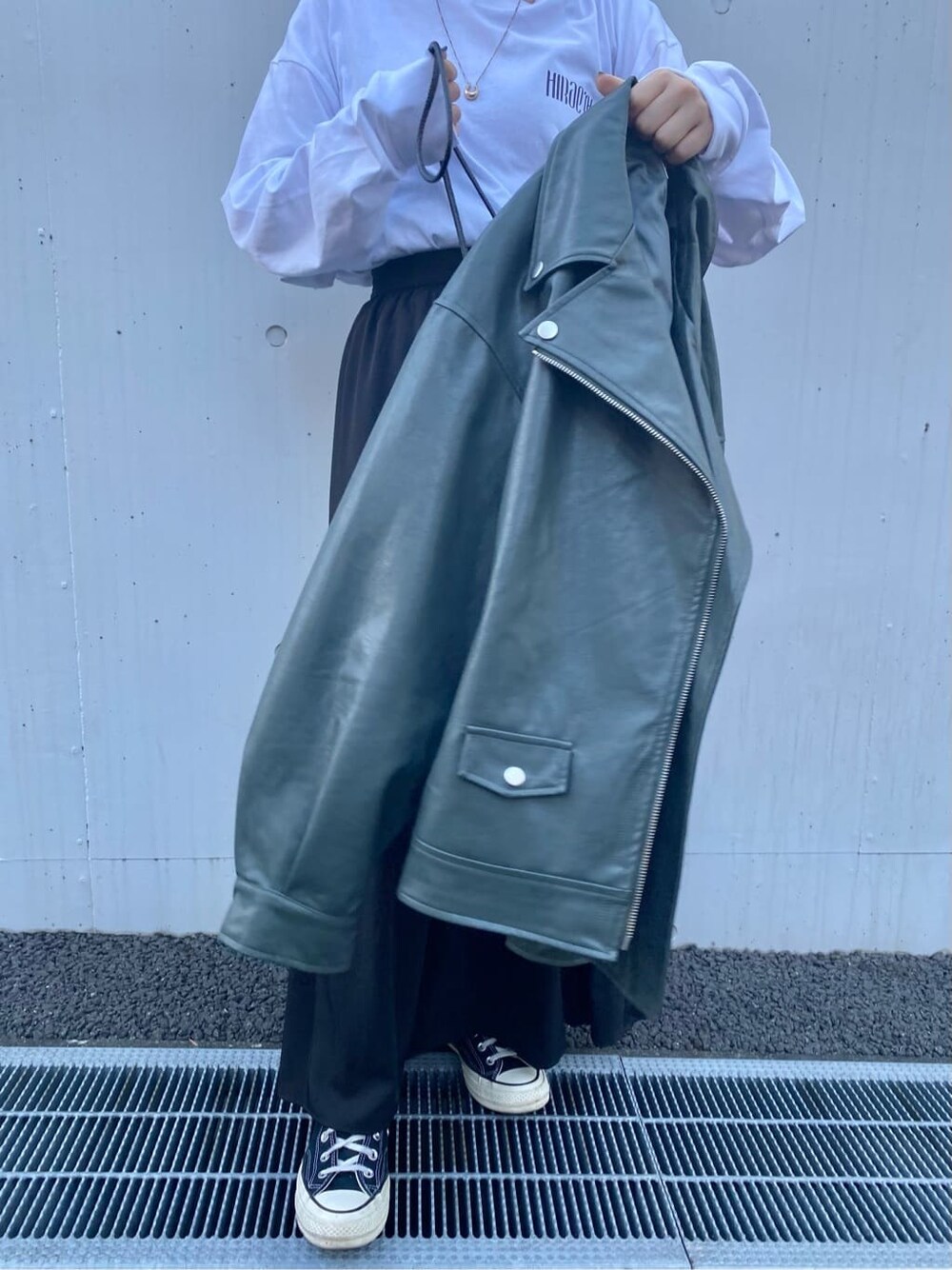 ホワイト系のTシャツ/カットソー、グリーン系のライダースジャケット、ブラック系のスカートを着用したレディースの秋コーディネートの4枚目の写真