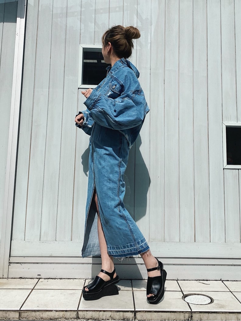 ブルー系のデニムスカート、グリーン系のニット/セーター、ブラック系のサンダルを着用したレディースの春コーディネートの2枚目の写真