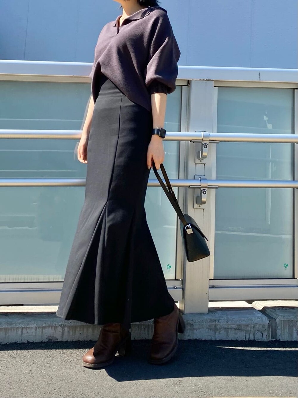 ブラック系のショルダーバッグ、ブラウン系のブーツ、ブラック系のスカートを着用したレディースの冬コーディネートの3枚目の写真