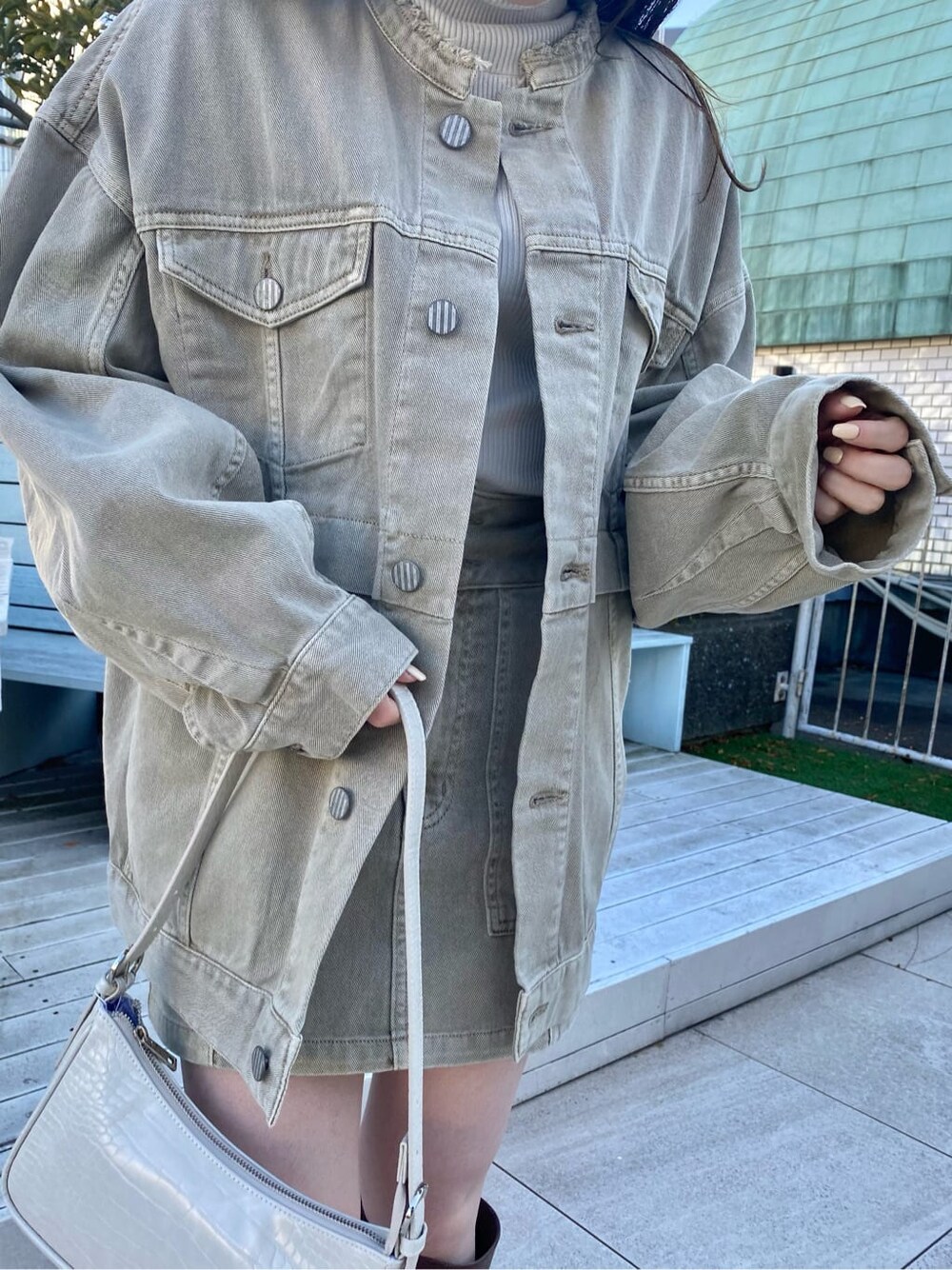 ブラウン系のブーツ、ホワイト系のニット/セーター、ベージュ系のデニムジャケットを着用したレディースの冬コーディネートの3枚目の写真