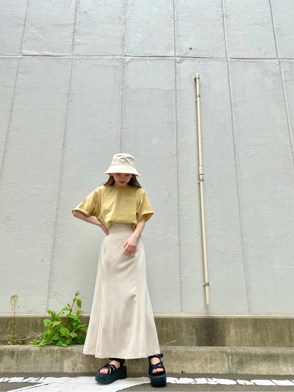 ブラック系のサンダル、イエロー系のTシャツ/カットソー、ホワイト系のハットを着用したレディースの春コーディネートの2枚目の写真
