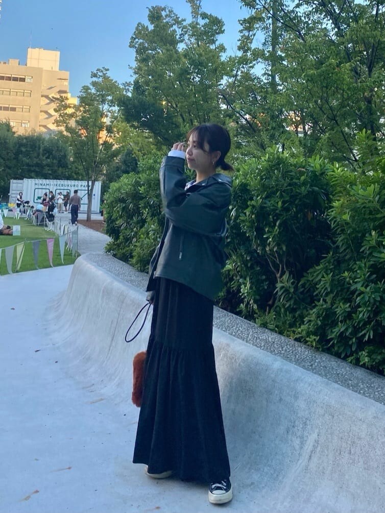 ホワイト系のTシャツ/カットソー、グリーン系のライダースジャケット、ブラック系のスカートを着用したレディースの秋コーディネートの2枚目の写真