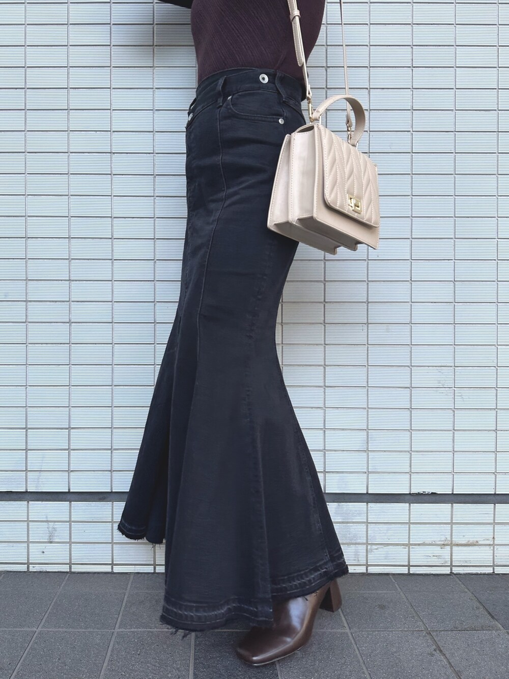 ブラウン系のニット/セーター、ブラック系のデニムスカート、ベージュ系のショルダーバッグを着用したレディースの秋コーディネートの7枚目の写真