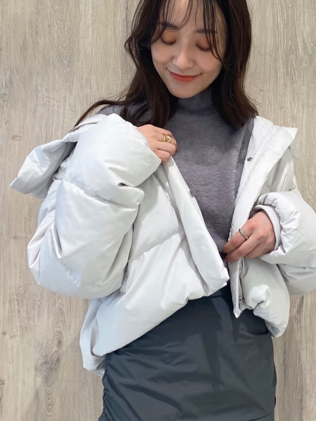 ホワイト系のダウンジャケット/コート、ブラック系のブーツ、パープル系のニット/セーターを着用したレディースの秋コーディネートの6枚目の写真