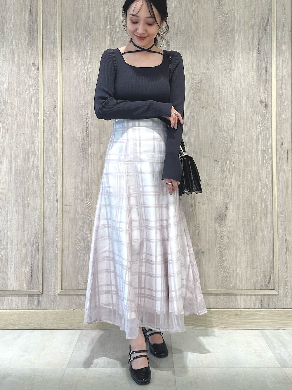 レッド系のハンドバッグ、ブラウン系のパンプス、グレー系のワンピースを着用したレディースの秋コーディネートの3枚目の写真