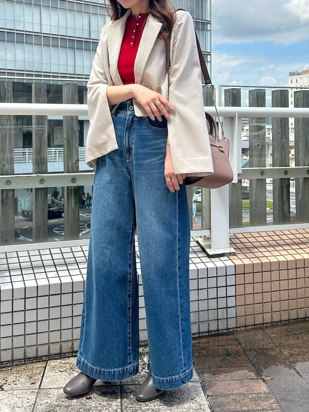 ブルー系のデニムパンツ、ブラウン系のブーツ、ブラウン系のハンドバッグを着用したレディースの夏コーディネートの3枚目の写真