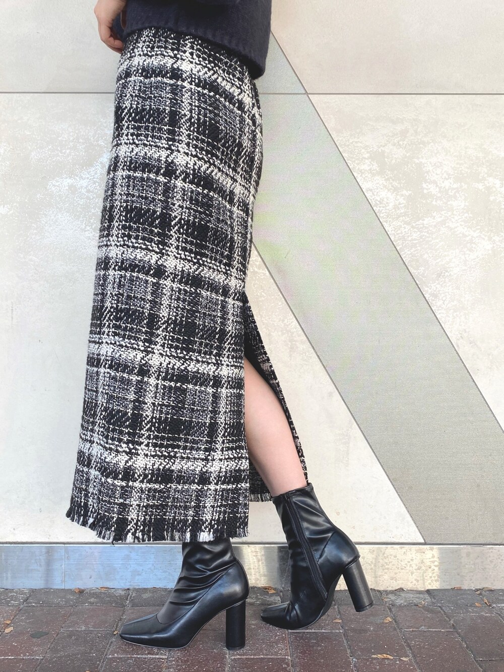 グレー系のニット/セーター、ブラック系のスカート、ブラック系のブーツを着用したレディースの秋コーディネートの8枚目の写真