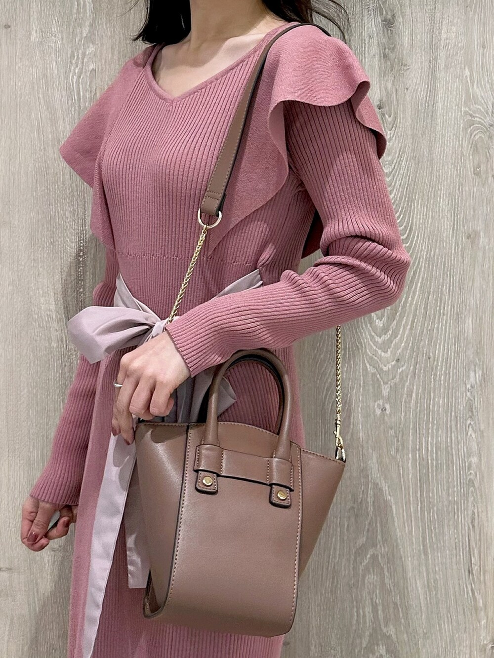 ピンク系のワンピース、ブラウン系のハンドバッグ、ブラウン系のブーツを着用したレディースの冬コーディネートの6枚目の写真