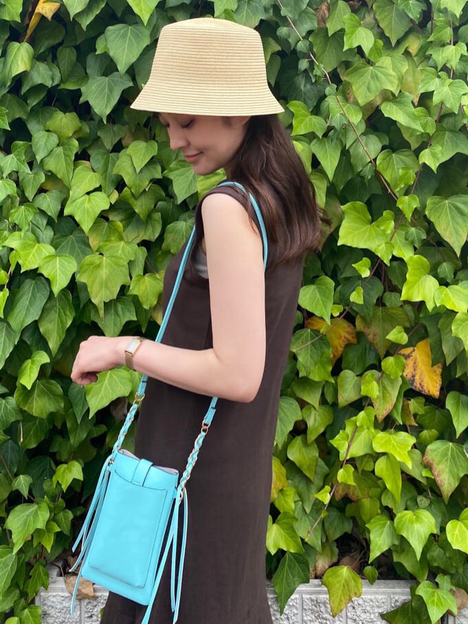グリーン系のショルダーバッグ、ブラウン系のサンダル、ベージュ系のキャミソールを着用したレディースの夏コーディネートの5枚目の写真