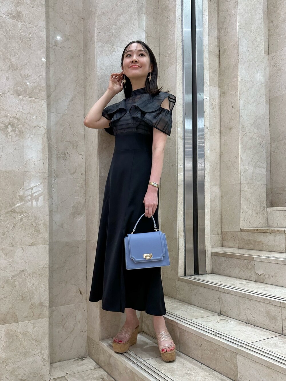 ブラック系のワンピース、ブルー系のハンドバッグ、その他のサンダルを着用したレディースの春コーディネートの2枚目の写真