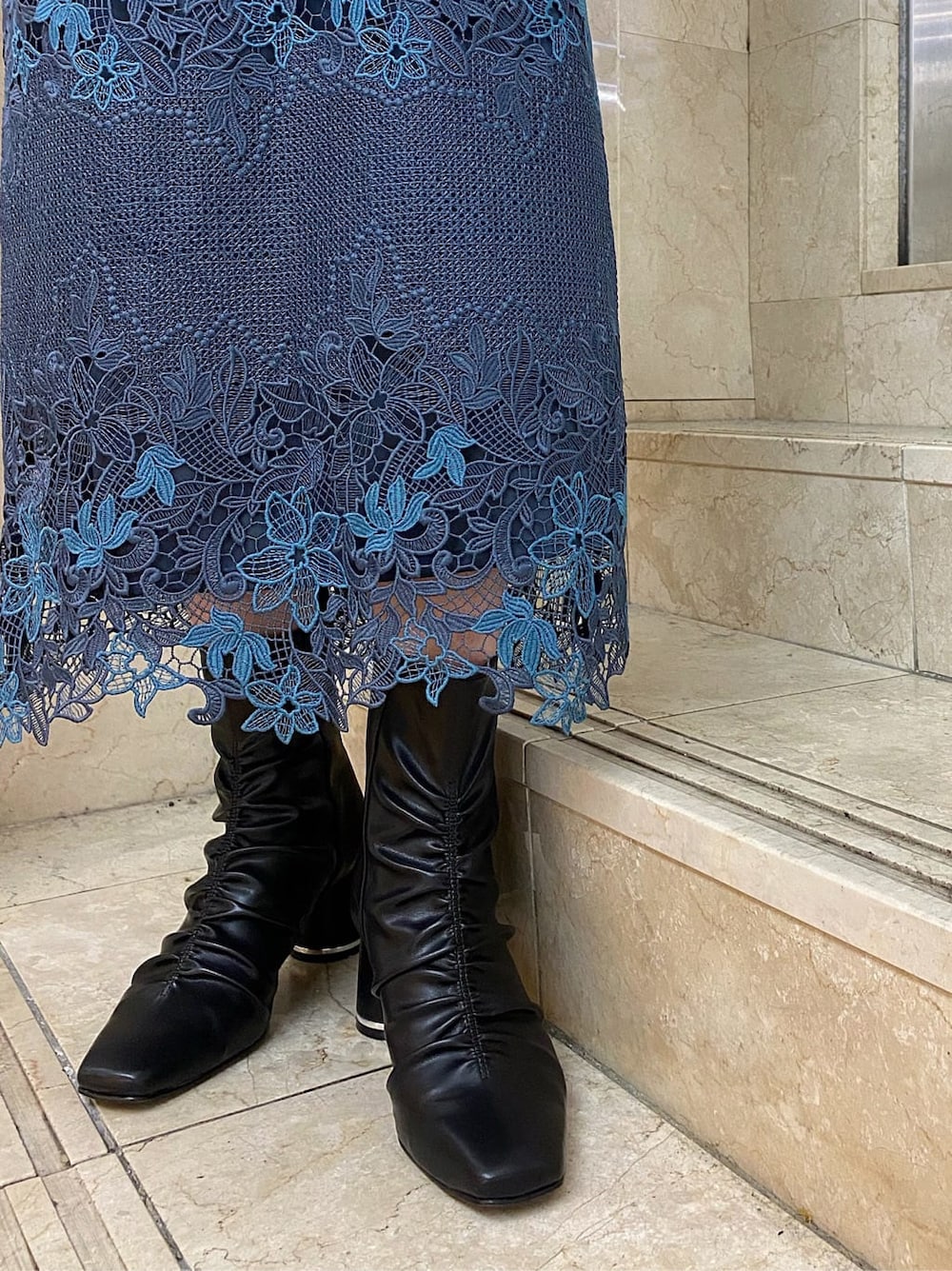 グリーン系のチェスターコート、ブルー系のスカート、ブラック系のその他シューズを着用したレディースの秋コーディネートの7枚目の写真