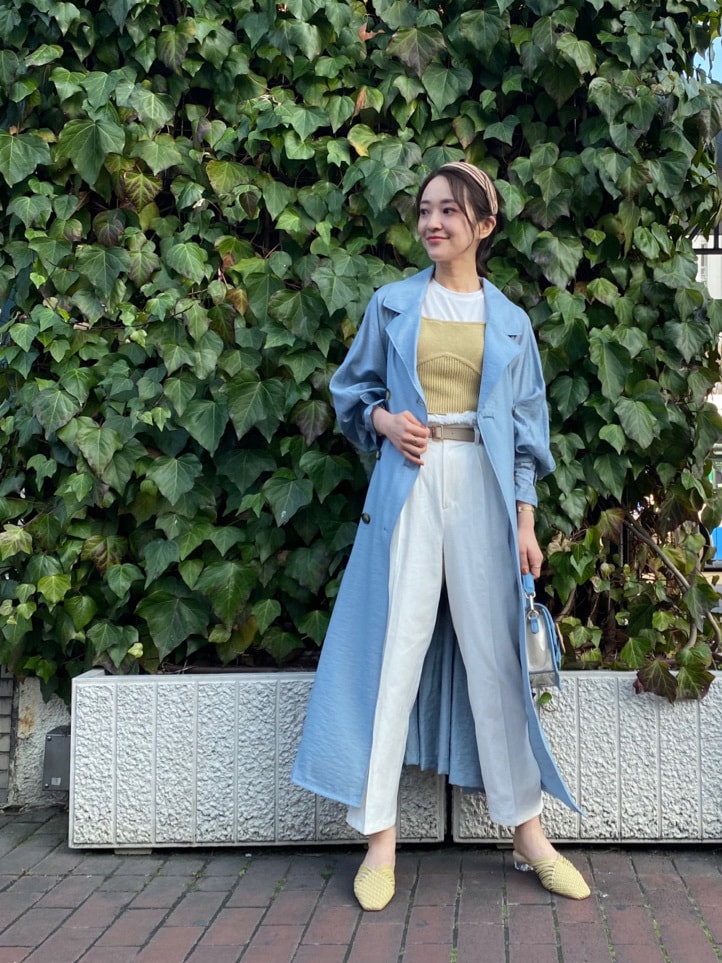 ブルー系のトレンチコート、イエロー系のサンダル、ホワイト系のその他パンツを着用したレディースの春コーディネートの3枚目の写真