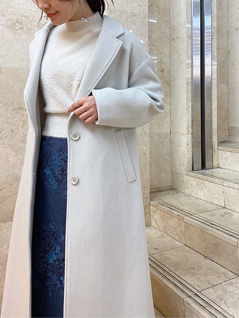 グリーン系のチェスターコート、ブルー系のスカート、ブラック系のその他シューズを着用したレディースの秋コーディネートの2枚目の写真