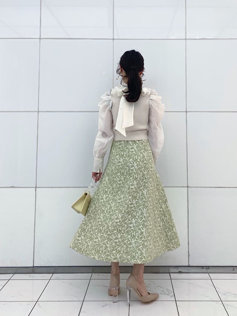 ベージュ系のパンプス、グリーン系のスカート、イエロー系のショルダーバッグを着用したレディースの冬コーディネートの4枚目の写真