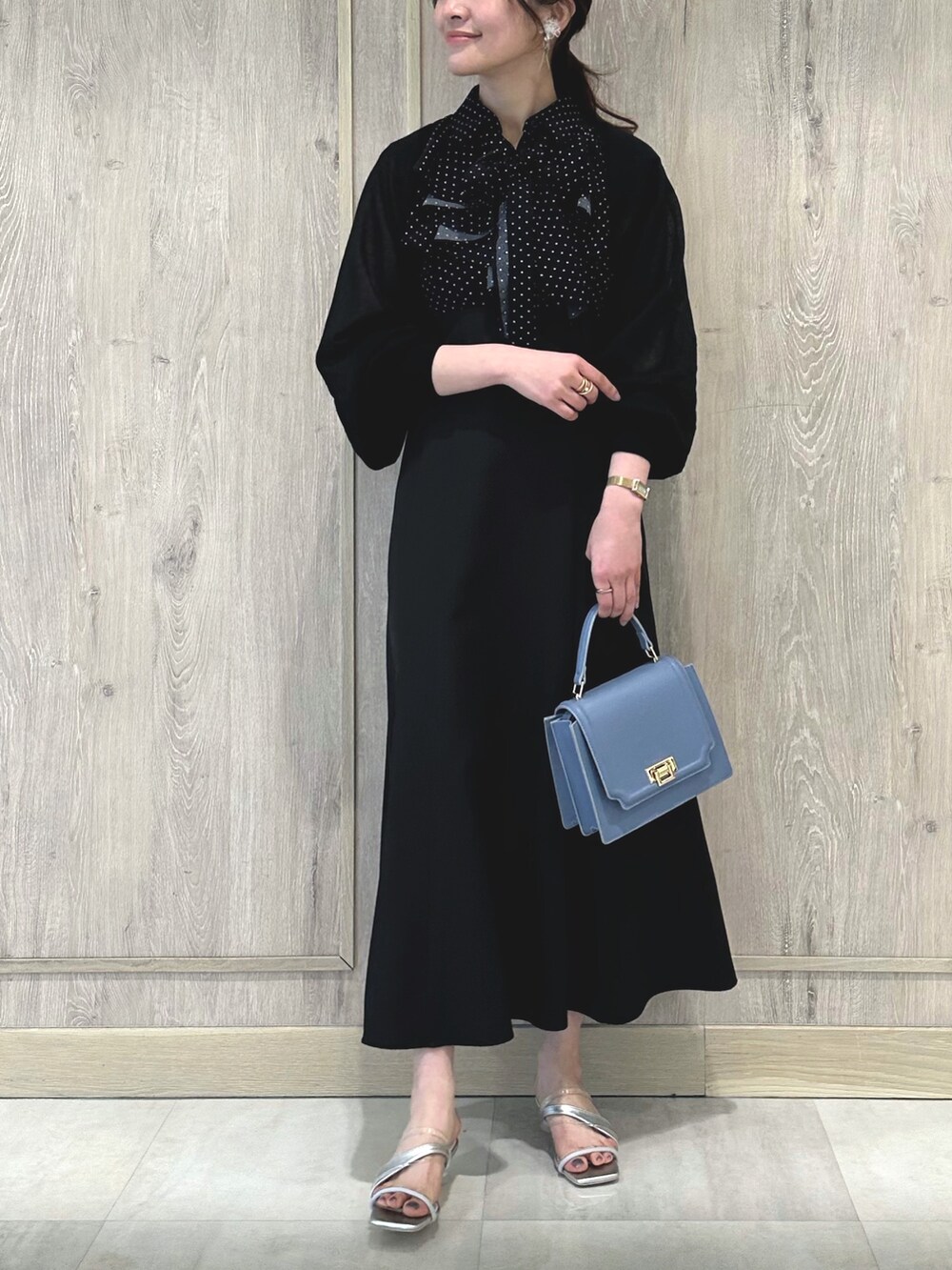 ブラック系のワンピース、ブルー系のハンドバッグ、シルバー系のサンダルを着用したレディースの春コーディネートの8枚目の写真