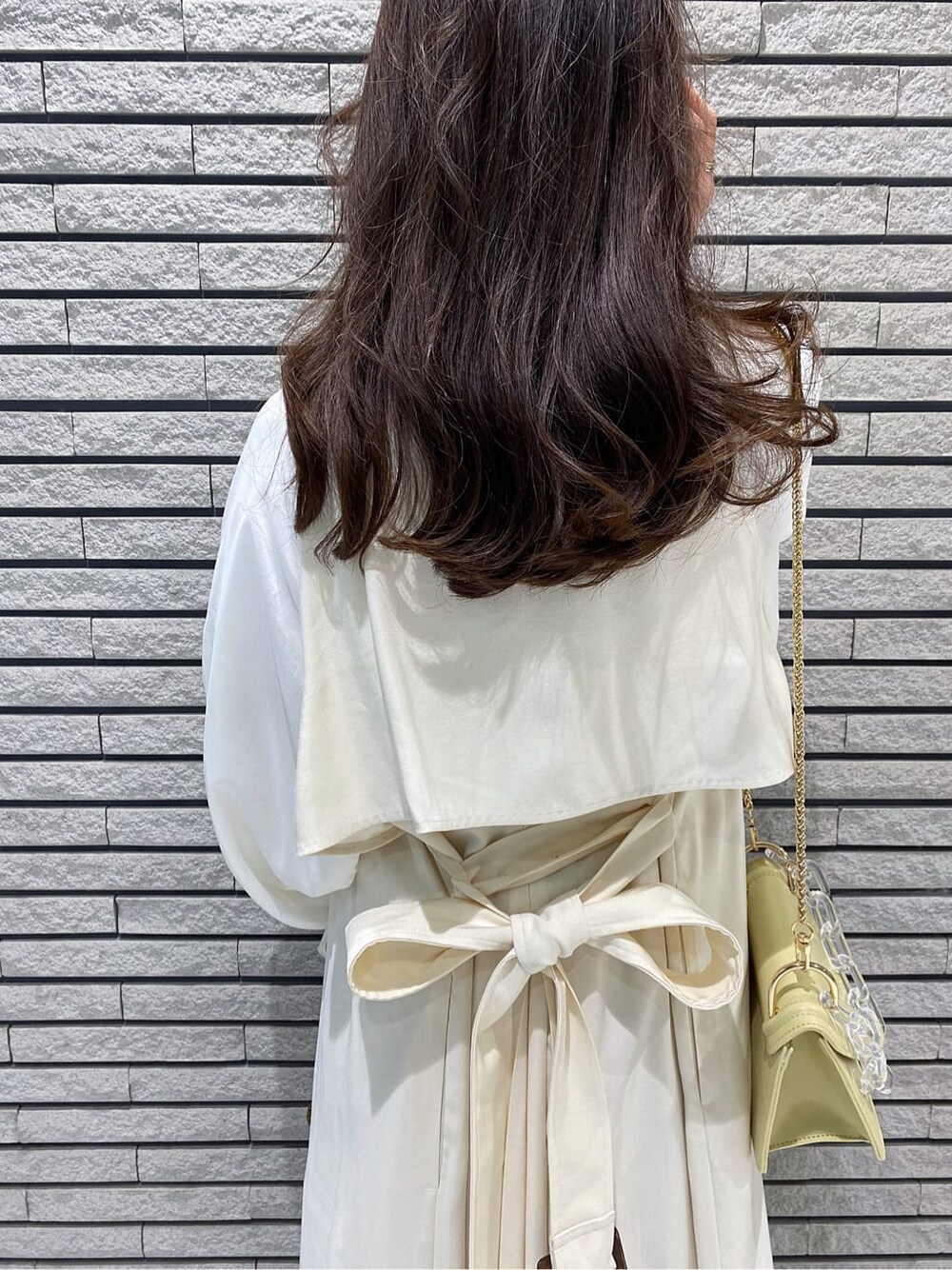 ホワイト系のその他アウター、イエロー系のショルダーバッグ、ベージュ系のワンピースを着用したレディースの冬コーディネートの6枚目の写真