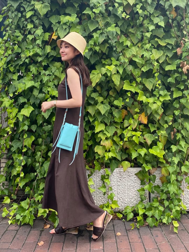 グリーン系のショルダーバッグ、ブラウン系のサンダル、ベージュ系のキャミソールを着用したレディースの夏コーディネートの4枚目の写真
