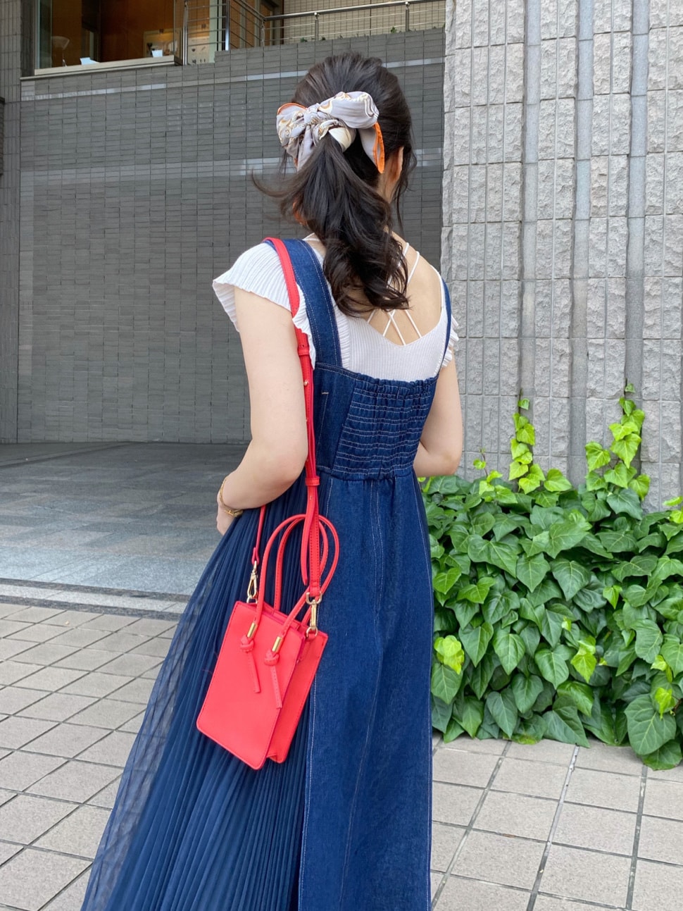 レッド系のハンドバッグ、ブルー系のワンピース、ホワイト系のニット/セーターを着用したレディースの夏コーディネートの7枚目の写真