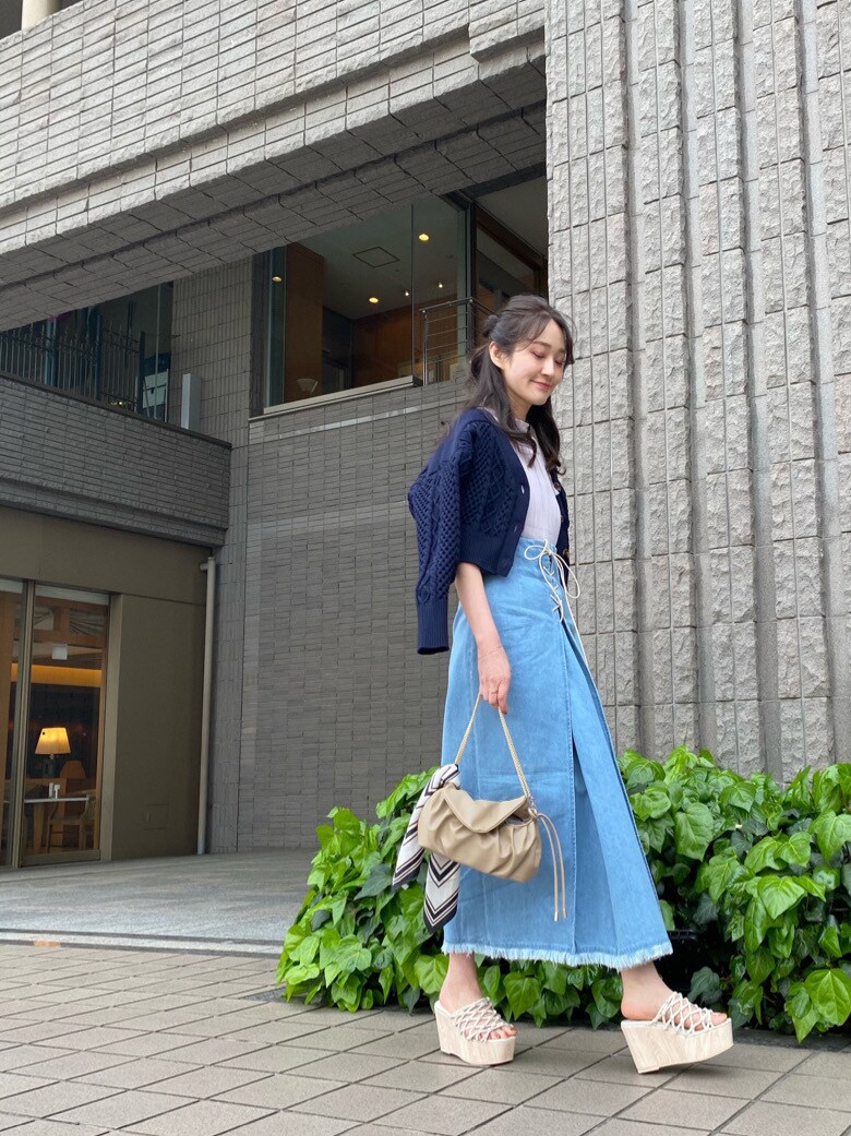 ベージュ系のクラッチバッグ、ホワイト系のサンダル、ブルー系のスカートを着用したレディースの春コーディネートの3枚目の写真
