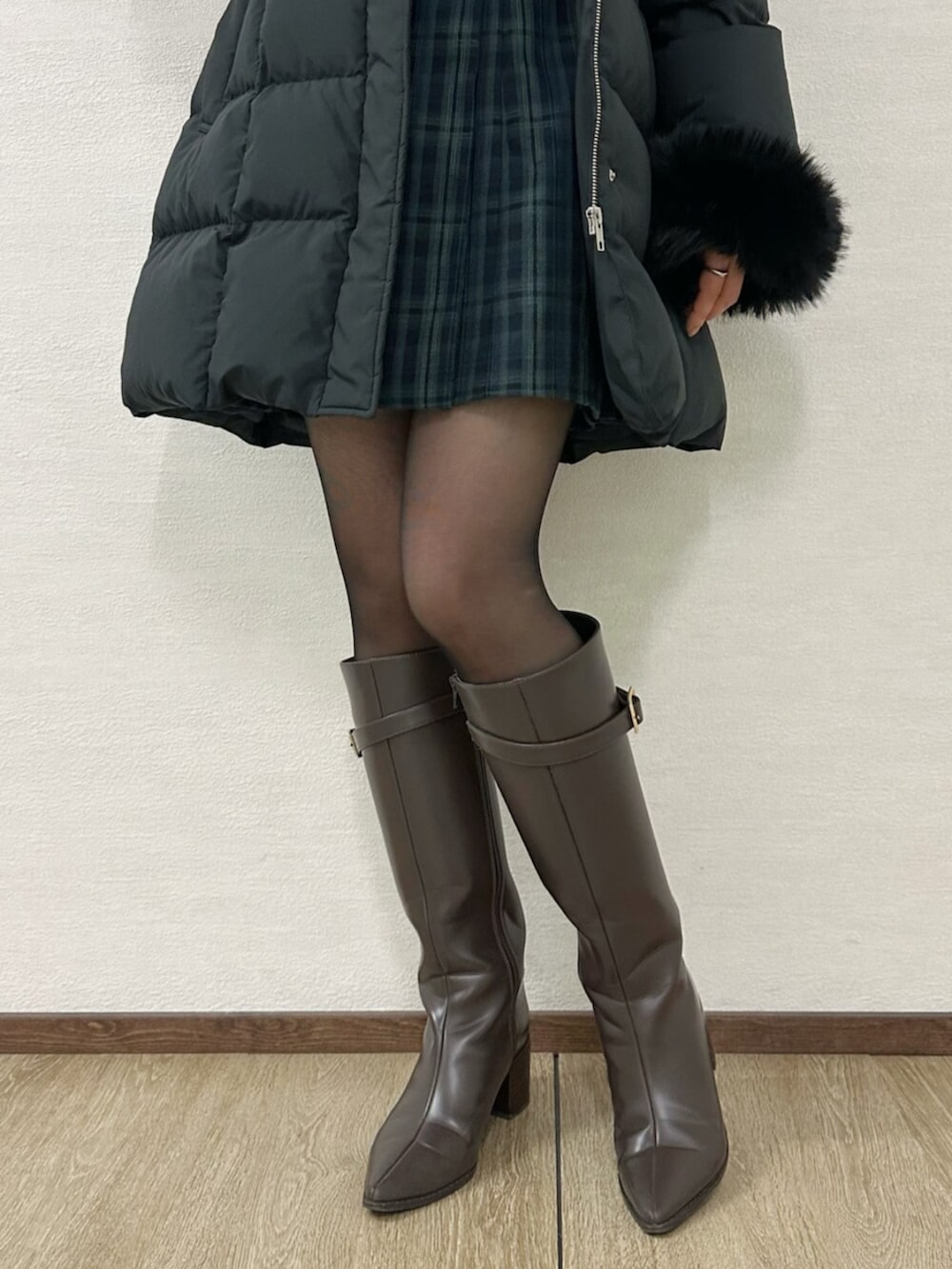 グリーン系のワンピース、ブラウン系のブーツ、ブラック系のダウンジャケット/コートを着用したレディースの冬コーディネートの5枚目の写真