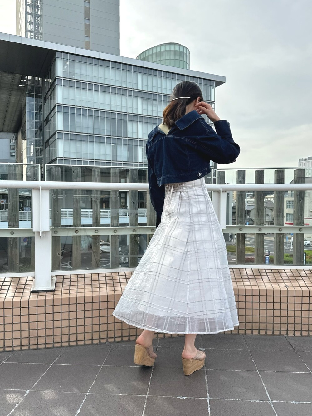 ホワイト系のハンドバッグ、グリーン系のワンピース、ブルー系のデニムジャケットを着用したレディースの春コーディネートの4枚目の写真