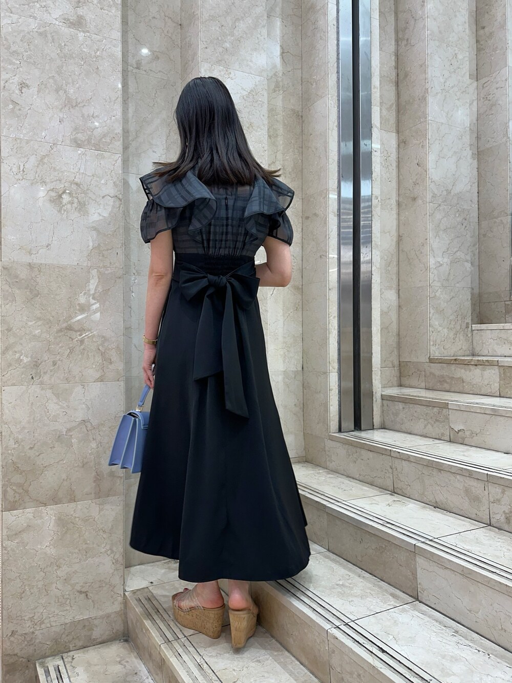 ブラック系のワンピース、ブルー系のハンドバッグ、その他のサンダルを着用したレディースの春コーディネートの4枚目の写真