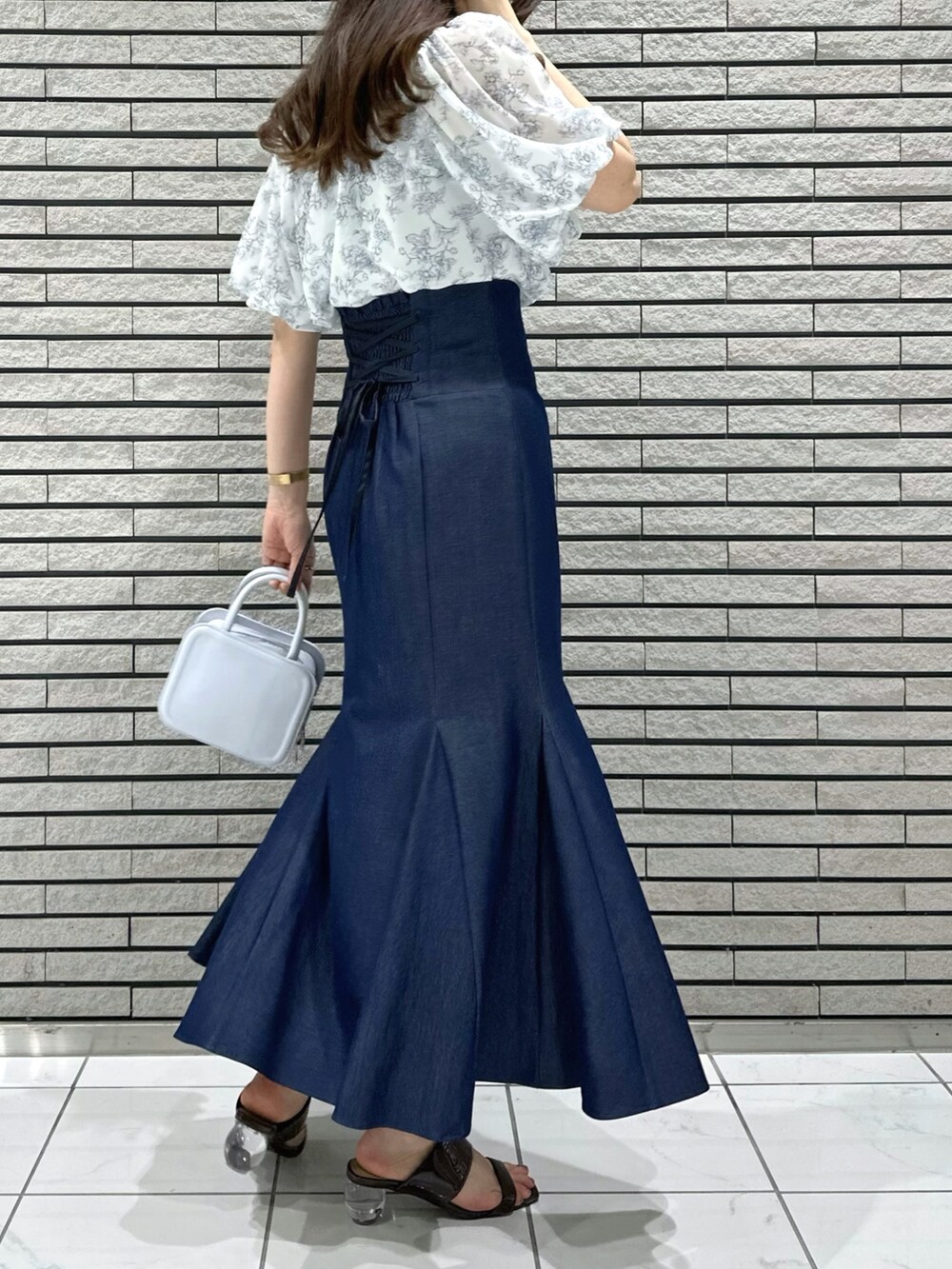 ブルー系のハンドバッグ、ブルー系のスカート、ブルー系のシャツ/ブラウスを着用したレディースの夏コーディネートの4枚目の写真