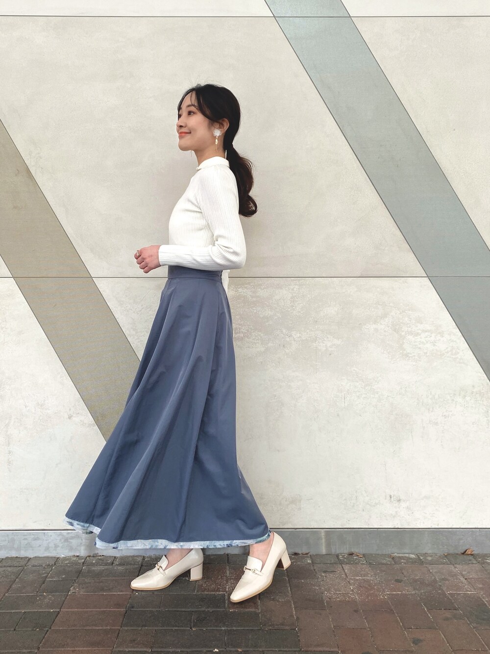 ブルー系のスカート、ホワイト系のニット/セーター、ホワイト系のキャミソールを着用したレディースの冬コーディネートの3枚目の写真