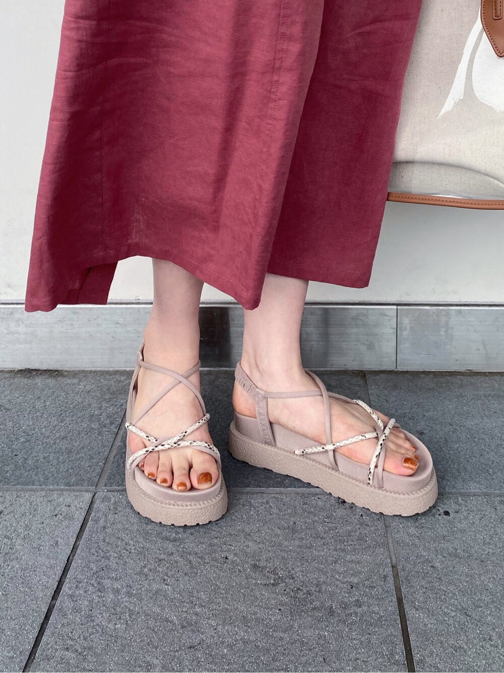 ブラウン系のトートバッグ、レッド系のワンピース、その他のサンダルを着用したレディースの夏コーディネートの8枚目の写真