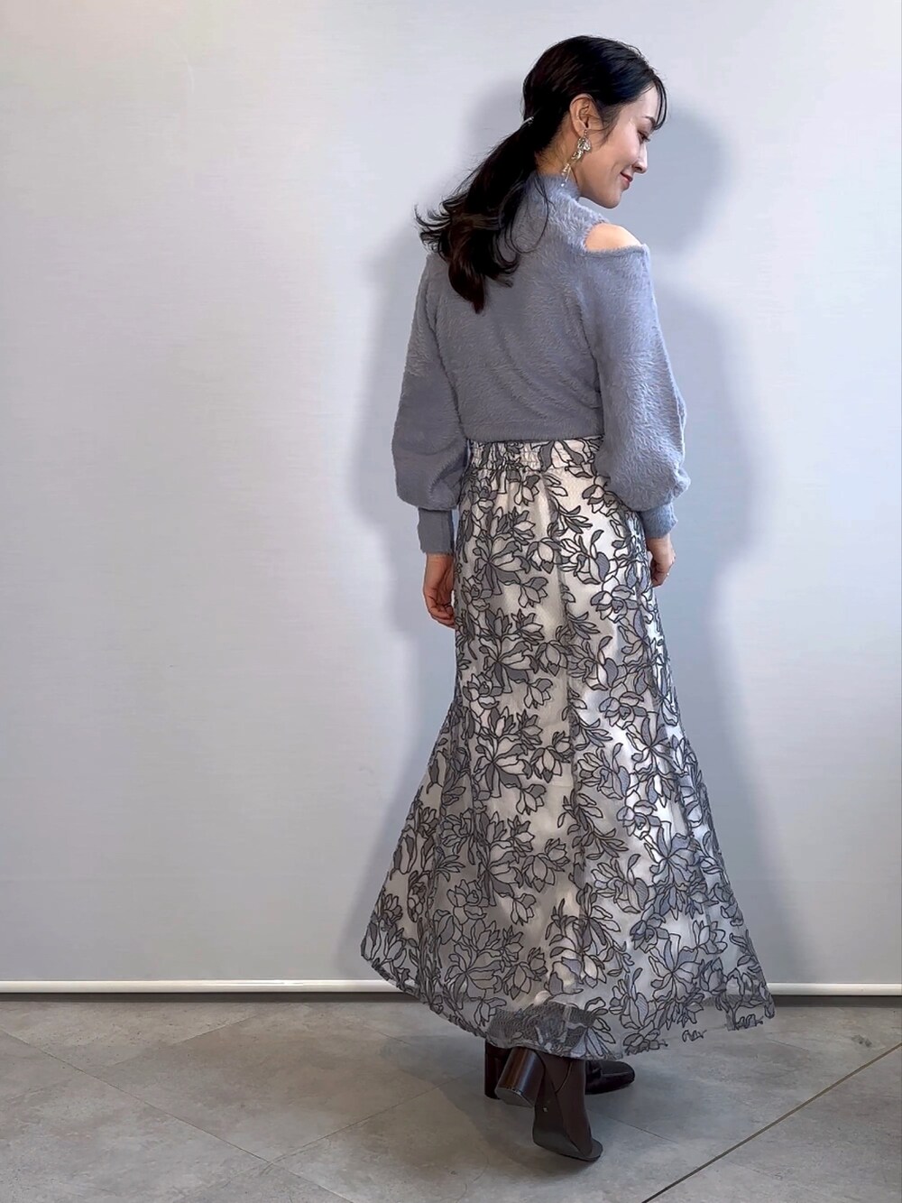 ブルー系のニット/セーター、グレー系のスカート、ブラウン系のブーツを着用したレディースの秋コーディネートの3枚目の写真