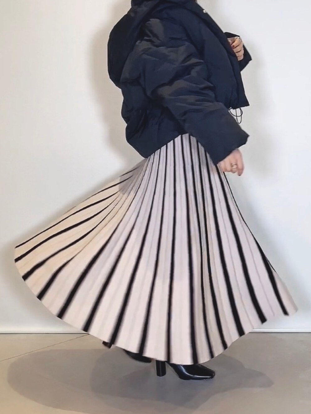 ブラック系のブーツ、ブラック系のワンピース、ブラック系のダウンジャケット/コートを着用したレディースの冬コーディネートの6枚目の写真