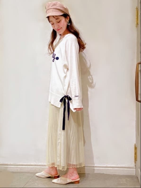 イエロー系のスカート、ベージュ系のパンプス、ホワイト系のニット/セーターを着用したレディースの冬コーディネートの2枚目の写真