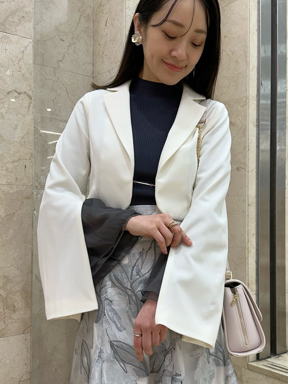 ホワイト系のテーラードジャケット、グレー系のスカート、グレー系のニット/セーターを着用したレディースの春コーディネートの5枚目の写真