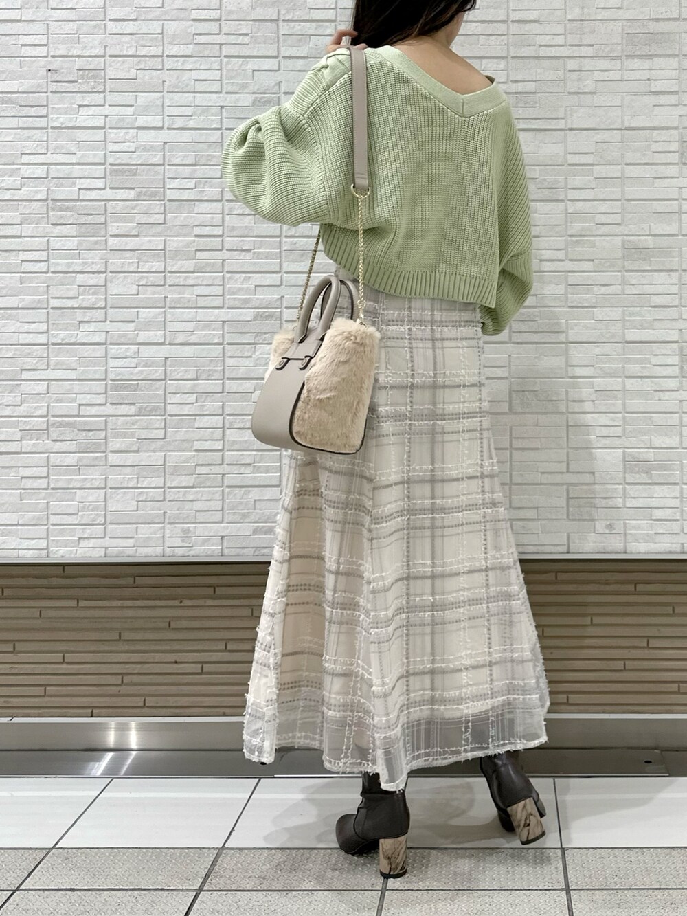 ホワイト系のハンドバッグ、グリーン系のカーディガン/ボレロ、ホワイト系のスカートを着用したレディースの秋コーディネートの4枚目の写真