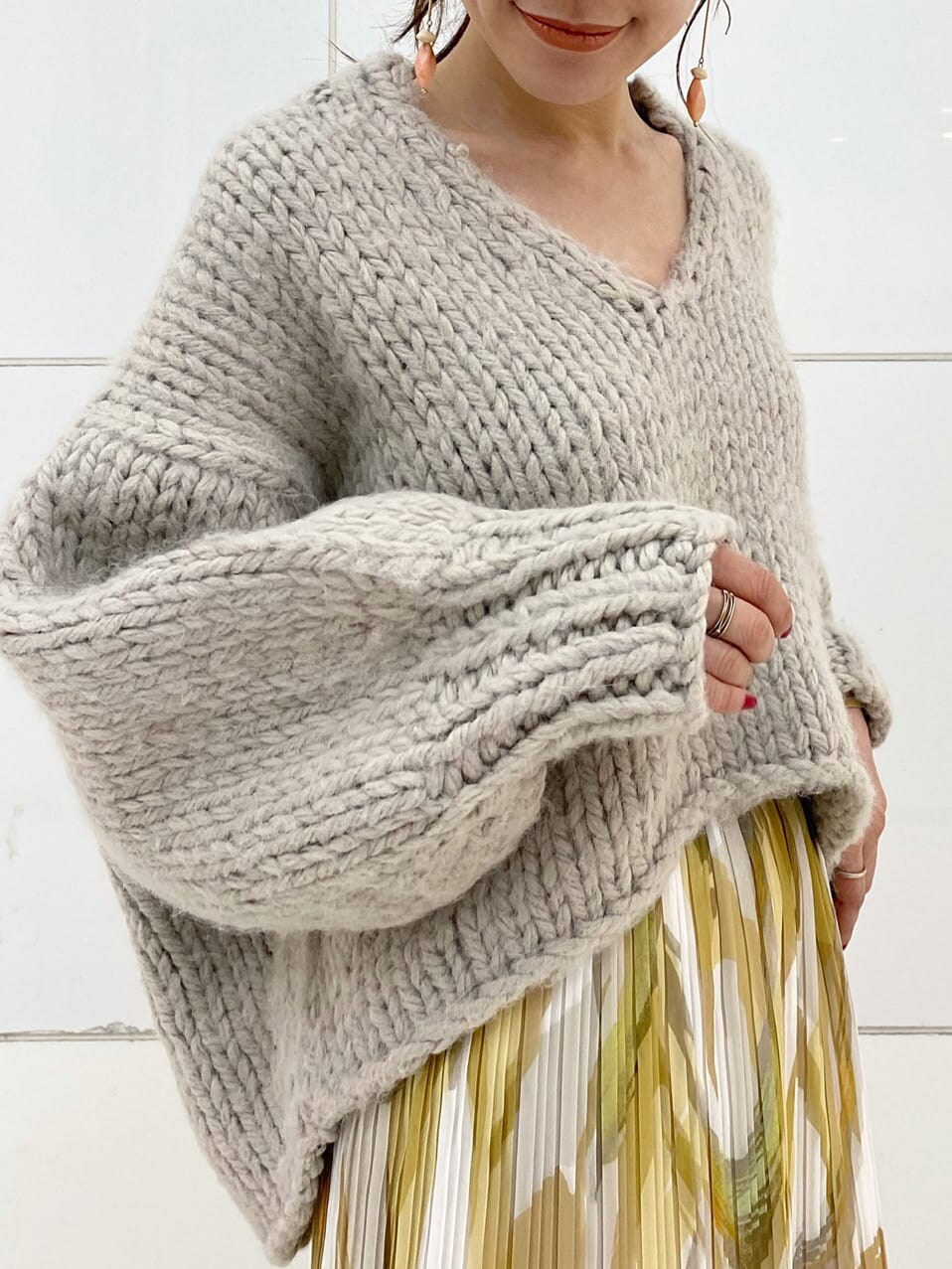 イエロー系のスカート、グレー系のニット/セーター、ベージュ系のブーツを着用したレディースの秋コーディネートの7枚目の写真