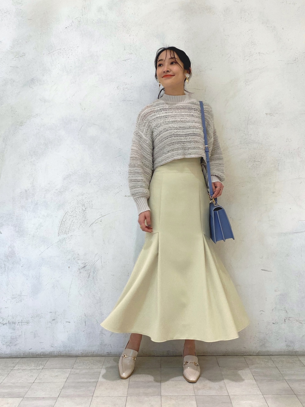 ホワイト系のローファー、イエロー系のスカート、ブルー系のハンドバッグを着用したレディースの冬コーディネートの2枚目の写真