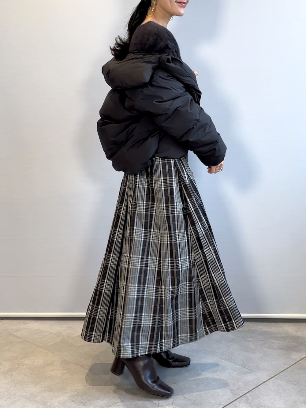 ブラック系のスカート、ブラウン系のブーツ、グレー系のニット/セーターを着用したレディースの冬コーディネートの2枚目の写真