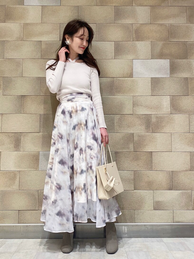 ベージュ系のトレンチコート、ベージュ系のトートバッグ、ホワイト系のニット/セーターを着用したレディースの冬コーディネートの2枚目の写真