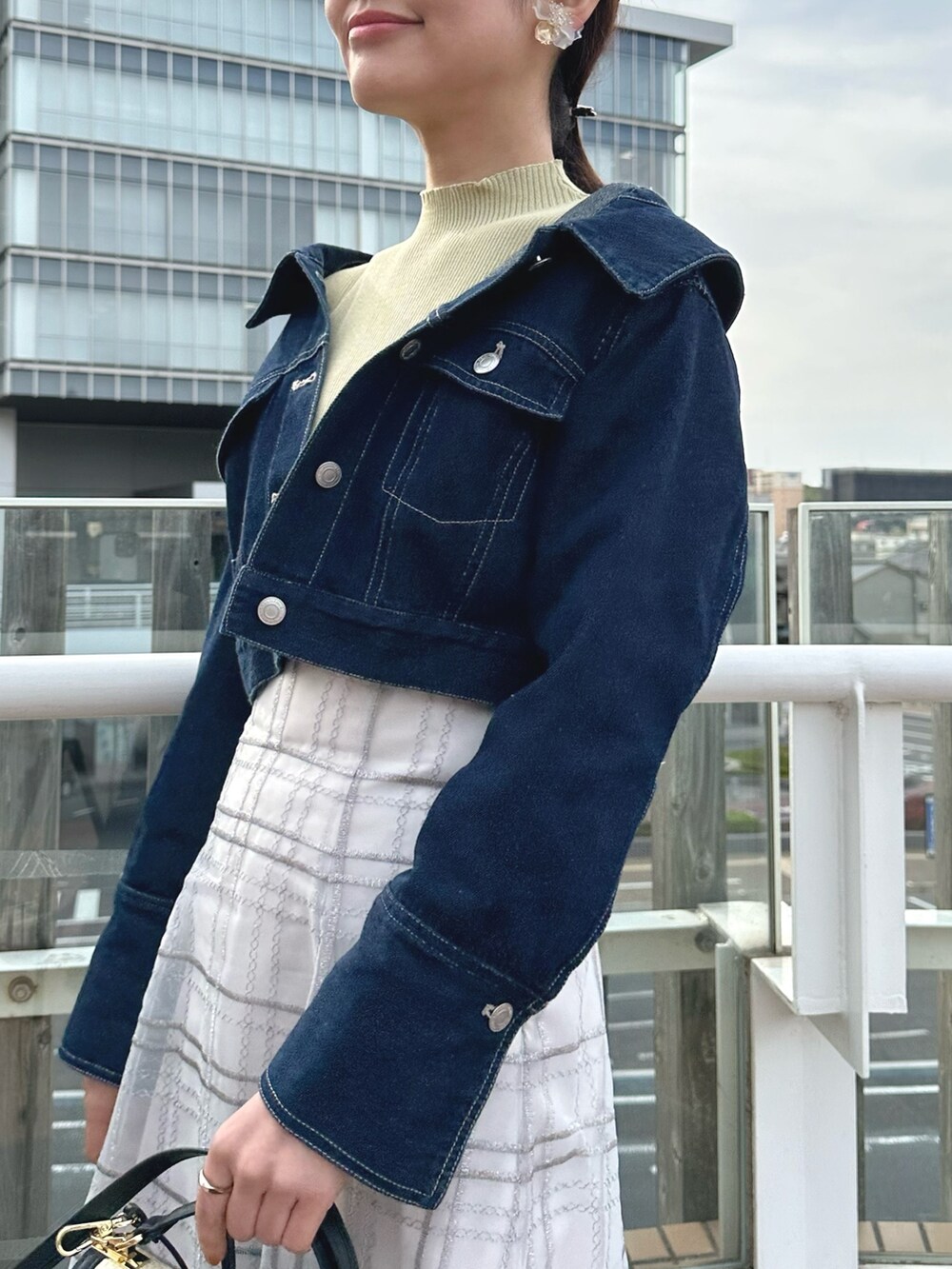 ホワイト系のハンドバッグ、グリーン系のワンピース、ブルー系のデニムジャケットを着用したレディースの春コーディネートの6枚目の写真